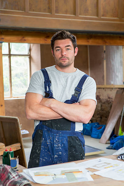 A young man stands with his arms folded looking at the camera